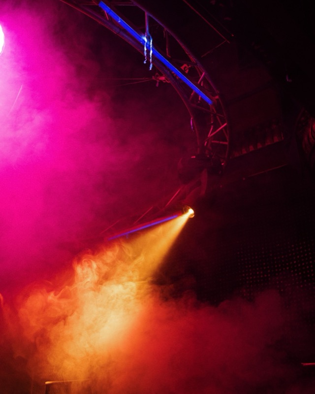 A club lighting rig above the crowd in pink and orange smoke.